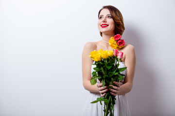 portrait of beautiful young woman with bouquet of roses on the wonderful studio background