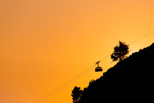 Cableway or ropeway to Mount Srdj in Dubrovnik, Croatia against the background of the orange sky.