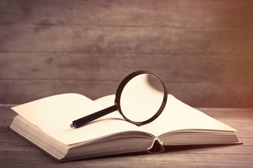 Fototapeta premium photo of opened notebook and magnifying glass on the wonderful brown wooden background