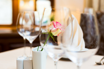 Pink rose in a vase as table decoration. Table setting
