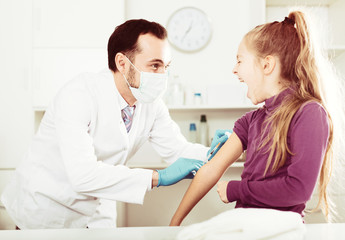 Male doctor injecting little patient
