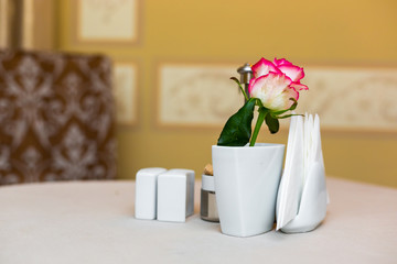 Pink rose in a vase as table decoration. Table setting