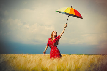 portrait of beautiful young woman with umbrella on the wonderful wheat field background