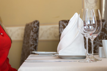 Durk in red is waiting at the restaurant. Table set service with silverware and glass stemware at restaurant before.