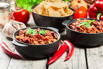 Bowls of hot chili con carne with ground beef, beans, tomatoes and corn