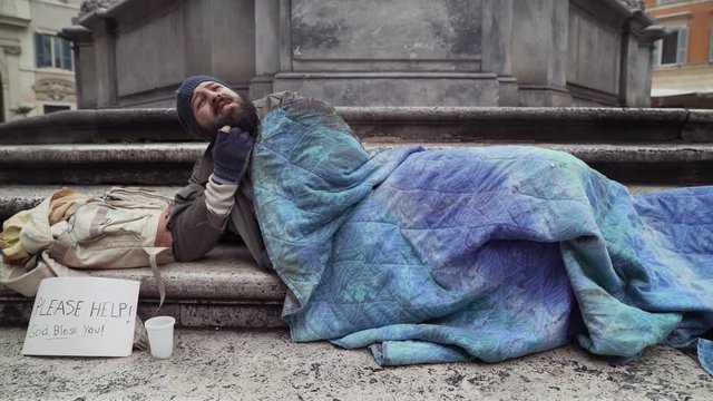 sleeping depressed beggar in the street wake up