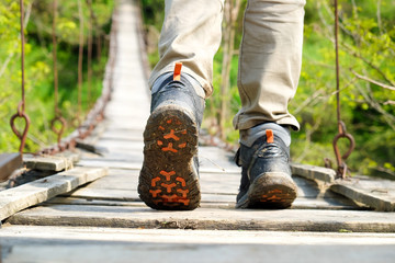 Hiker crossing wooden bridge over river