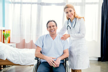 Obraz premium elderly man sitting in wheelchair and doctor standing near him in hospital