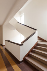 Brown staircase, white wall and large windows