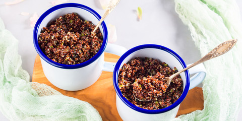 Red quinoa with vegetables in enamel mugs. Vegetarian gluten free lunch