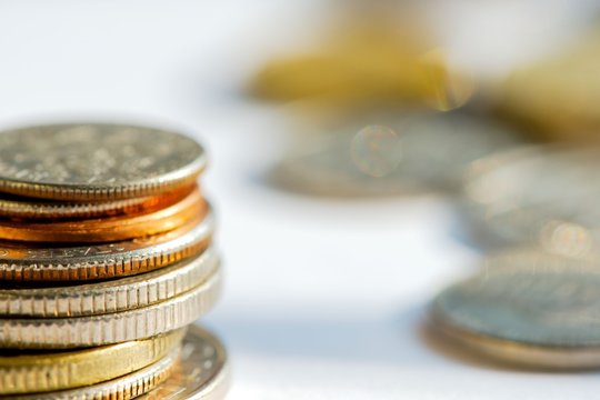 Golden and silver coins in a stack against a blurred background. Business, finance and money concept