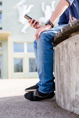 Junger Mann mit Telefon in der Hand - Closeup auf Füße