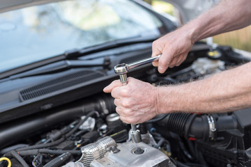 Hands of car mechanic working on car engine