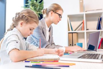 mother and daughter in office, girl drawing while businesswoman working