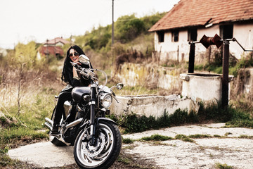 Fototapeta premium Beautiful brunette woman with a classic motorcycle (cinema bleach bypass effect)