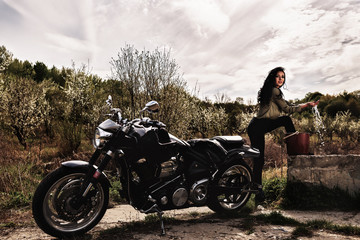 Beautiful brunette woman with a classic motorcycle (cinema bleach bypass effect)