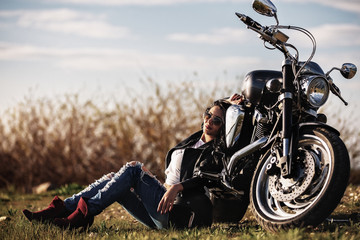 Beautiful brunette woman with a classic motorcycle (cinema bleach bypass effect)