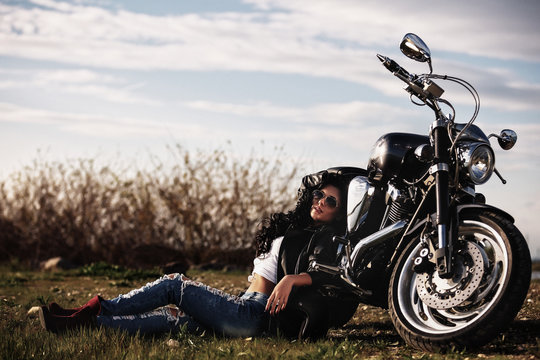 Beautiful brunette woman with a classic motorcycle (cinema bleach bypass effect)