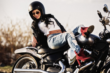 Beautiful brunette woman with a classic motorcycle (cinema bleach bypass effect)