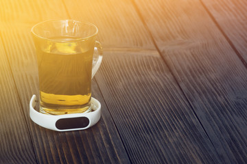 Fitness tracker and a cup of green tea on wooden table