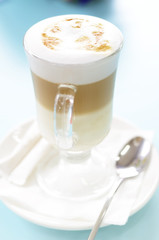 Latte macchiato cup on a blue table. Soft selective focus picture.
