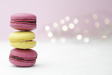 Pink and yellow macarons over an old white wooden table and pink background