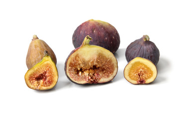 Several varieties of ripe common figs cut through to show the flesh and seeds on white background.