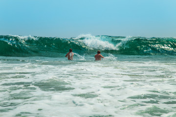 Two men dive into the waves.