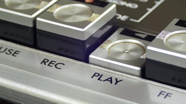 Pushing Play Button on a Vintage Tape Recorder. Close-up. Pushing a Finger Button Play. Man finger presses playback control buttons on audio cassette player.