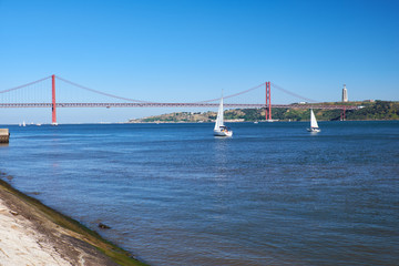 25th of April Bridge suspension bridge over river Tejo with Jesus Christ the King Statue on background in Lisbon. Portugal