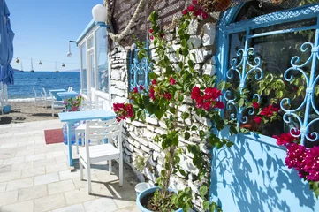Fotobehang Scenic view of Turkish alley with bougainvillea flowers growing along a wall in classic Mediterranean colors leading to the beach © lazyllama