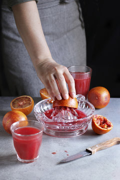 Female making blood orange juice with  a citrus hand squeezer