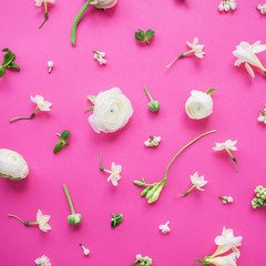 Floral pattern of white ranunculus, snapdragon, freesia and buds on pink background. Flat lay, top view. Summer background.