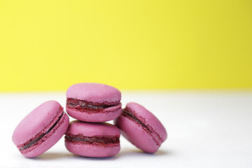 Pink macarons over an old white wooden table and yellow background