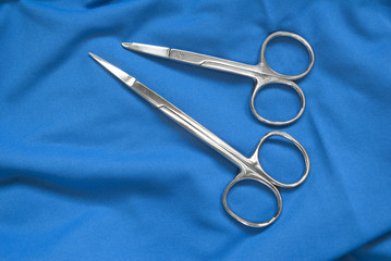 Two Surgical and suture Scissors on top of blue fabric