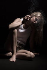 sad smoking blond girl thinker on black background