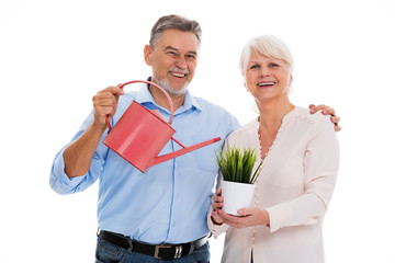 Senior couple with watering can and a plant
