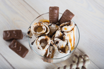 Roll of ice cream with crushed caramel candy. Fresh fried ice cream, ice roll on a light wooden background. Ice cream with caramel