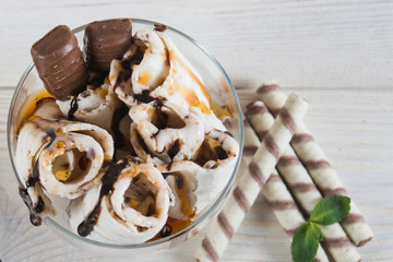 Roll of ice cream with crushed caramel candy. Fresh fried ice cream, ice roll on a light wooden background. Ice cream with caramel