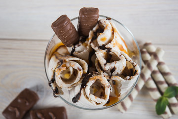 Roll of ice cream with crushed caramel candy. Fresh fried ice cream, ice roll on a light wooden background. Ice cream with caramel