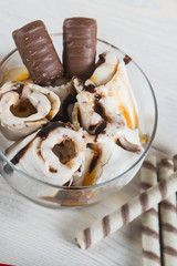 Roll of ice cream with crushed caramel candy. Fresh fried ice cream, ice roll on a light wooden background. Ice cream with caramel
