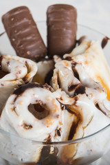 Roll of ice cream with crushed caramel candy. Fresh fried ice cream, ice roll on a light wooden background. Ice cream with caramel