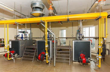 Interior of industrial gas boiler house with many pipes and boilers