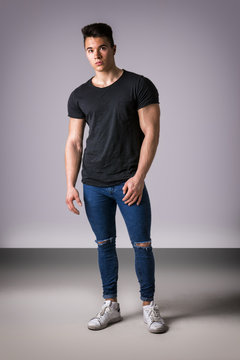 Handsome Young Muscular Man Looking At Camera In Studio Shot Over Neutral Background. Full Length Body Shot