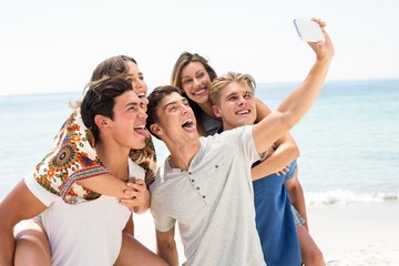 Friends taking selfie at beach on sunny day