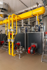 Interior of industrial gas boiler house with many pipes and boilers