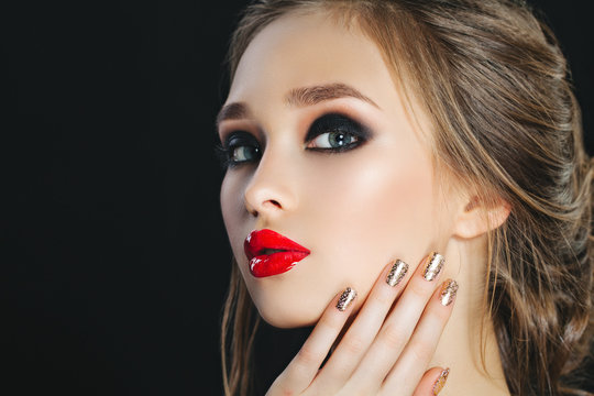 Beauty Woman with Perfect Makeup and brown hairs. Beautiful Professional Holiday Make-up. Smoky eyes. Red Lips  Nails,  eyebrows.  Girl's Face isolated on dark background. Copy-space