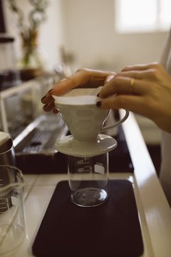 Female barista hands holding filter funnel and coffee mug