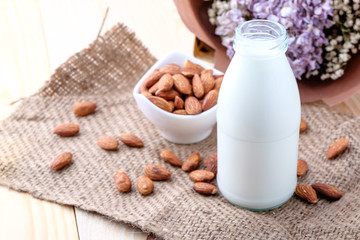 Obraz na płótnie Canvas Almond milk in glass bottle on wood background
