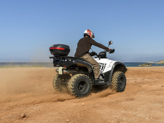 Fototapeta na wymiar A man riding ATV in sand in a helmet.